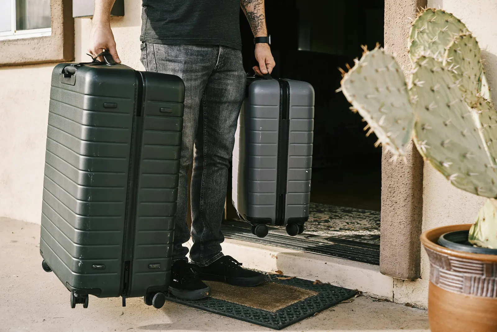 Home Traveller standing beside two black suitcases