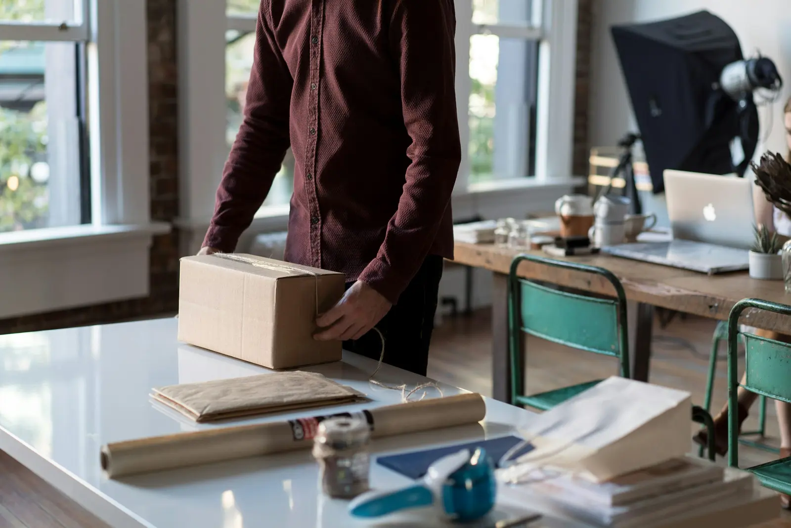 Home Person preparing a cardboard parcel for shipment at a desk